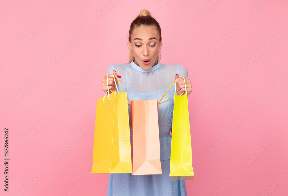 Young lady holding shopping bags looking inside Young lady holding shopping bags looking inside