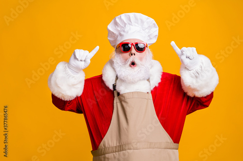 Photo of amazed santa claus point index finger chef hat christmas x-mas holly jolly meal preparation wear sunglass apron isolated over bright shine color background