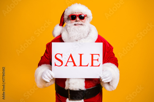 Portrait of his he nice attractive cheerful cheery confident fat Santa holding in hands board sale advert announcement black Friday isolated bright vivid shine vibrant yellow color background
