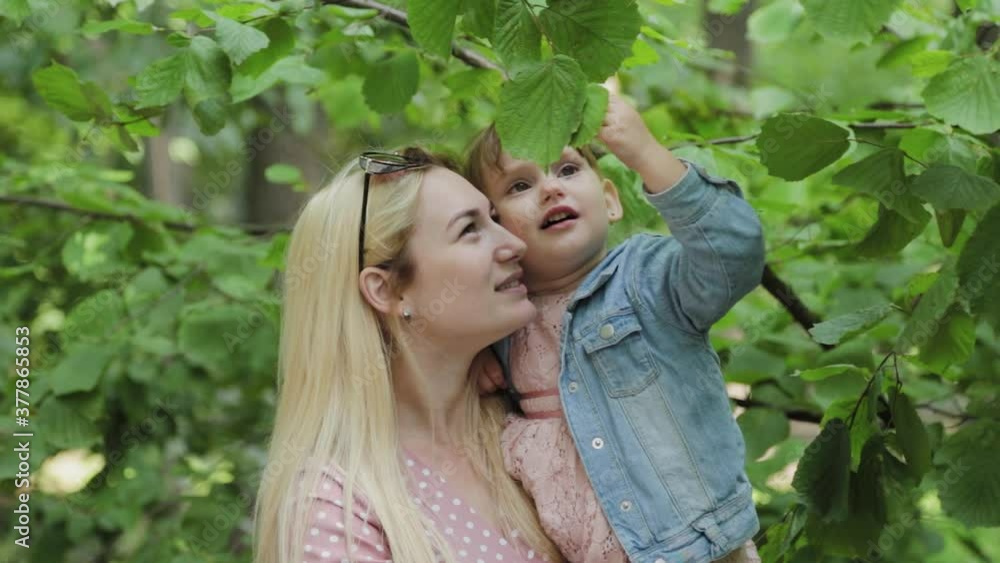 Happy young mother with little daughter near the tree in the park. Happy young mother with little daughter near the tree in the park.
