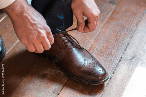 Close up view of man tying up brown shoes. Groom wearing elegant shoes on wedding day. 