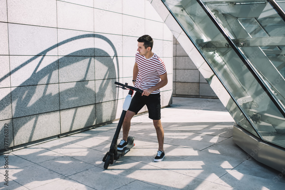 Obraz premium Young man preparing to ride scooter in modern lane