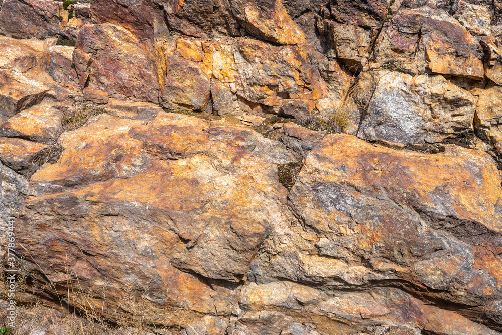 Rusted granite texture. Rusted stone background. Granite rocks. Colorful Rock background. Old Cracked Rusty Rough texture. Grunge Abstract Stone Surface.