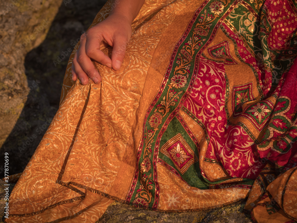 Female meditating on rocks with ethnic dress.