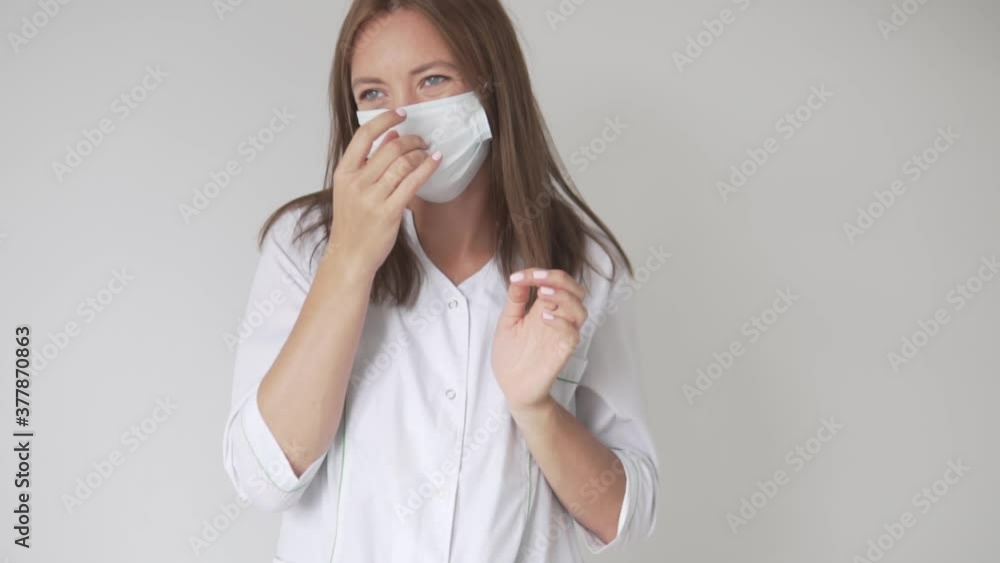 A beautiful woman Doctor removes the protective mask from the face and scratches her nose. A beautiful woman Doctor removes the protective mask from the face and scratches her nose.