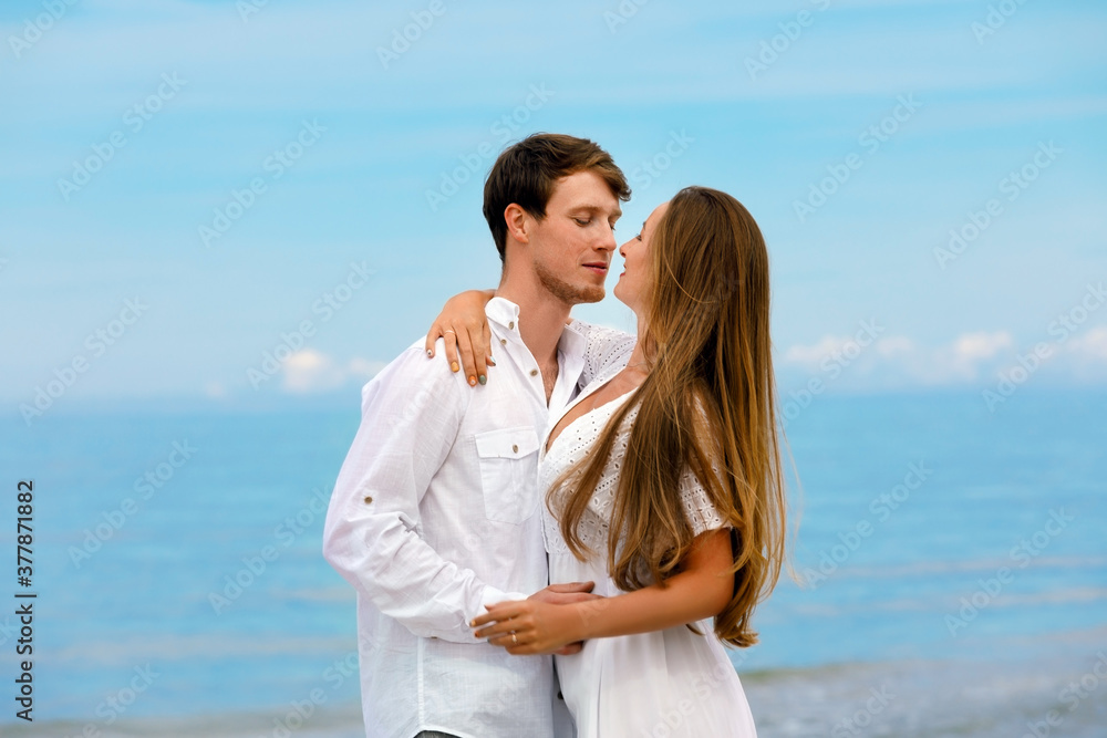 Sweet couple of young people in love hugging on the sea coast