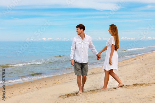 Cute couple of young lovers walk along the beach