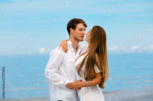 Sweet couple of young people in love hugging on the sea coast