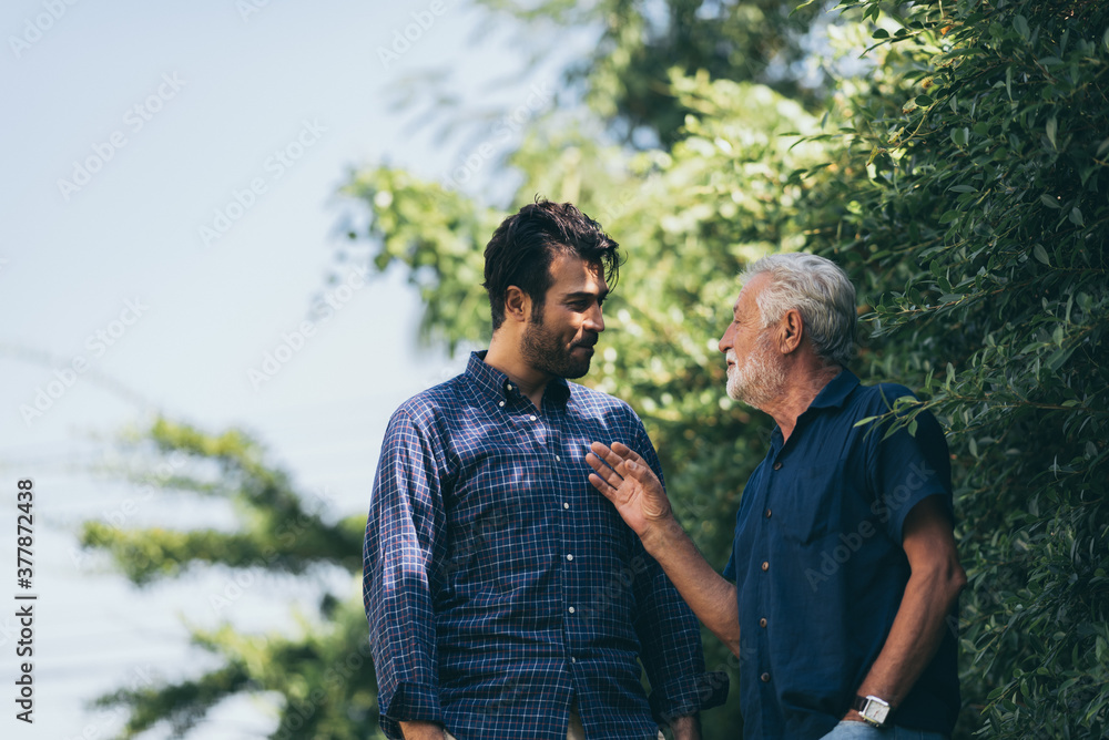 The happy elderly father and son spent time togerther with smiliing, laughing and talking at cozy home garden. Concept of freindly family The happy elderly father and son spent time togerther with smiliing, laughing and talking at cozy home garden. Concept of freindly family