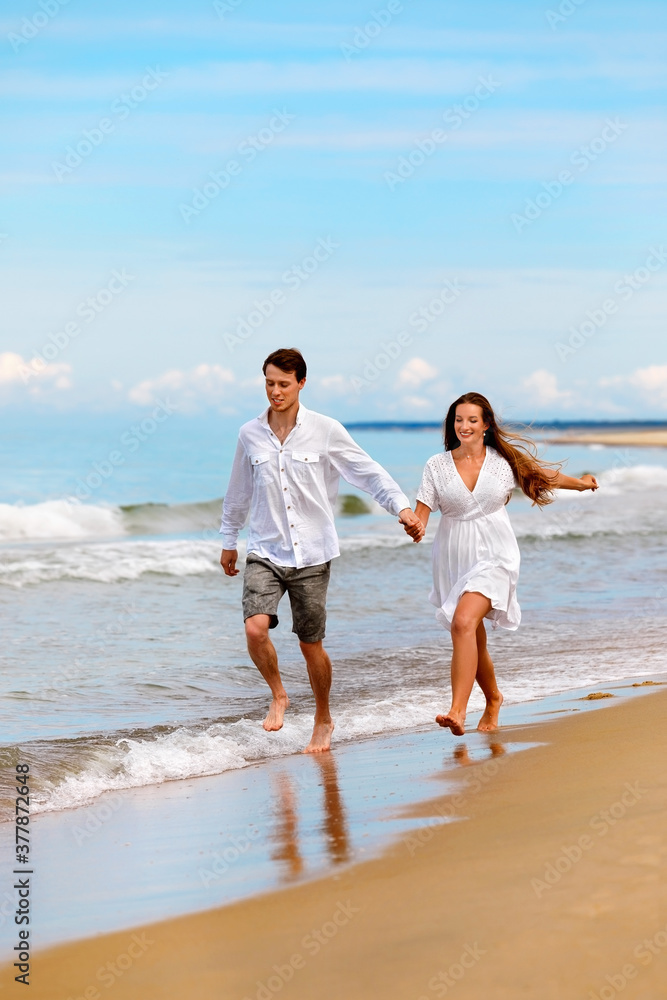 Nice couple of young people in love have fun on the sea coast