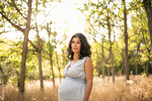 Pretty pregnant woman posing looking at camera in outdoors image