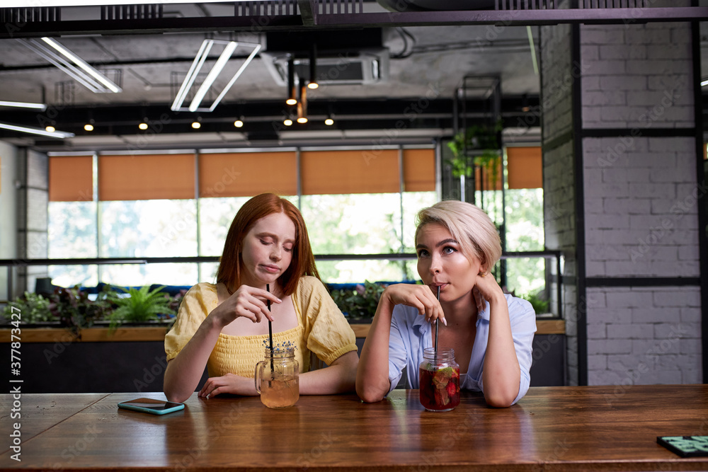 two caucasian ladies are bored of spending time at the bar, sit depressed and unhappy, want to go out