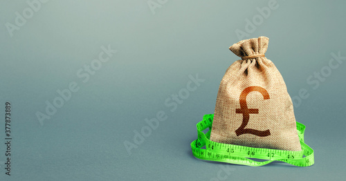 British pound sterling money bag and measuring tape meter. Analysis of economic situation. Formation and optimization of the budget, savings. Assessment of capital. Declaration of income, illegal.