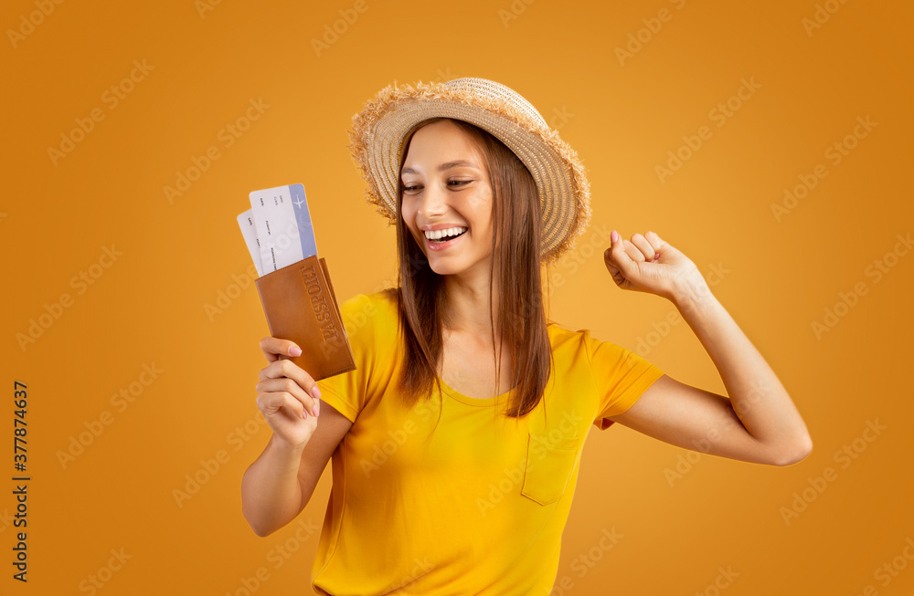 Emotional girl looking at passport with tickets in her hand Emotional girl looking at passport with tickets in her hand