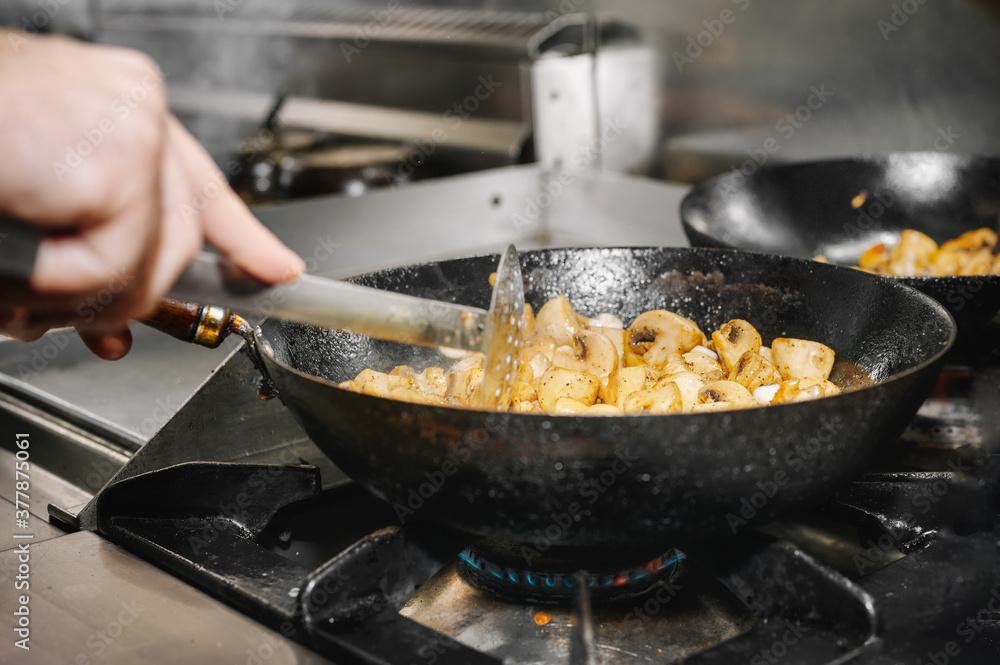 Chef cooking mushrooms in frying pan on burning fire. High quality image. Chef cooking mushrooms in frying pan on burning fire. High quality image.