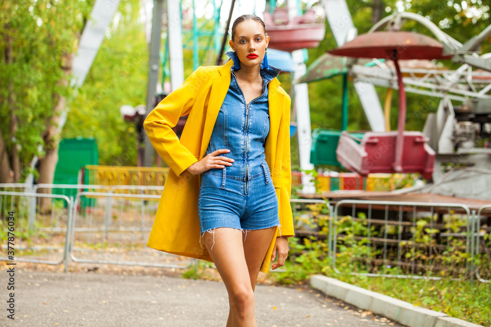 Young woman in yellow coat and denim overalls