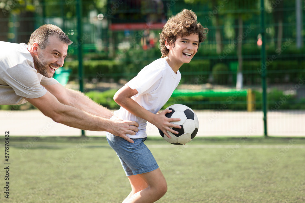 Dad spending time with his son at playground, playing soccer
