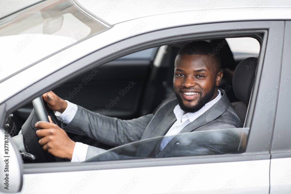 Handsome black businessman smiling while driving car