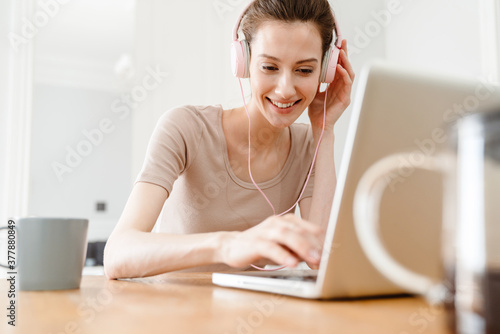 Image of cheerful girl working with laptop while sitting at table photo