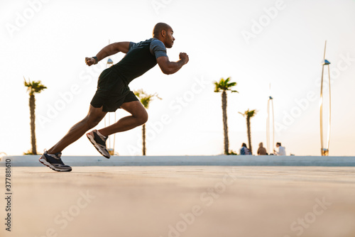 Handsome strong sportsman running on a street