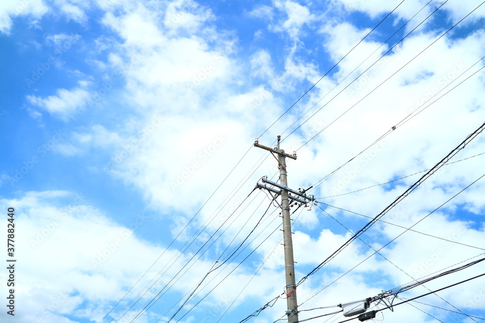 青空と白い雲を背景に撮影した電柱と電線