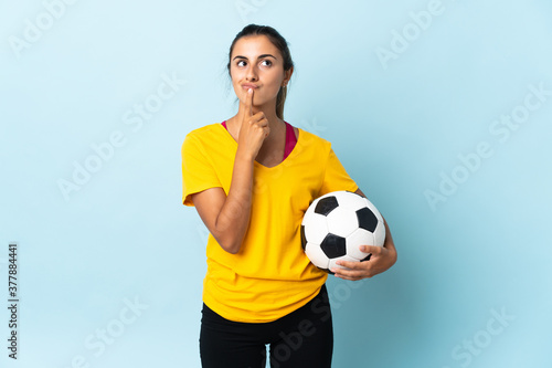 Young hispanic football player woman over isolated on blue background having doubts while looking up © luismolinero