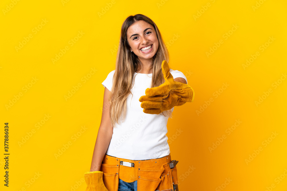Young hispanic electrician woman over isolated yellow wall shaking hands for closing a good deal Young hispanic electrician woman over isolated yellow wall shaking hands for closing a good deal