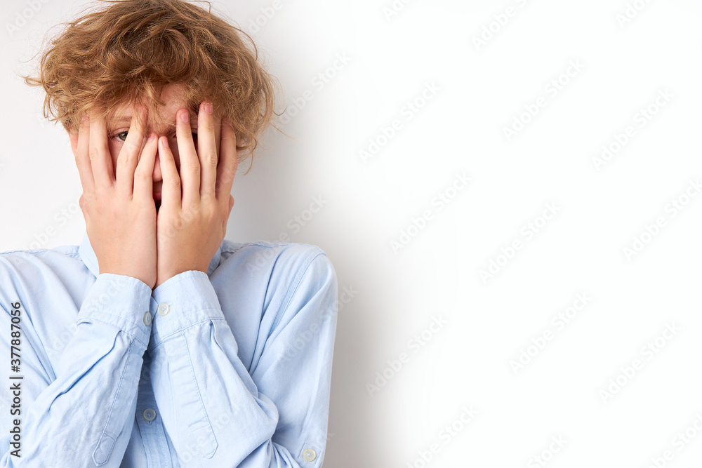 frightened boy closed his face with hands, 14-15 years old caucasian teenager is ashamed or he saw something terrible frightened boy closed his face with hands, 14-15 years old caucasian teenager is ashamed or he saw something terrible
