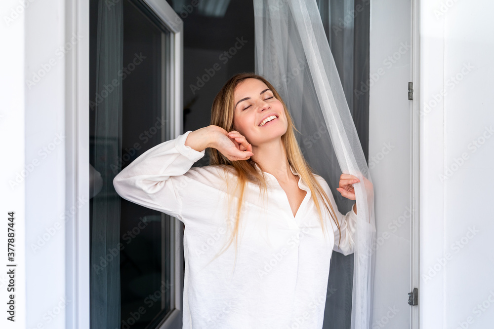 Relaxed young woman looking through window at the morning in home