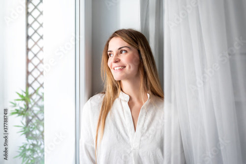 Relaxed young woman looking through window at the morning in home Free Download Relaxed young woman looking through window at the morning in home - GFXLoad