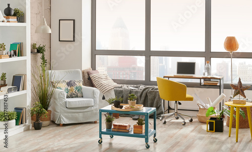 Living room interior style, city view background, armchair working table and laptop, middle coffee table style. © UnitedPhotoStudio