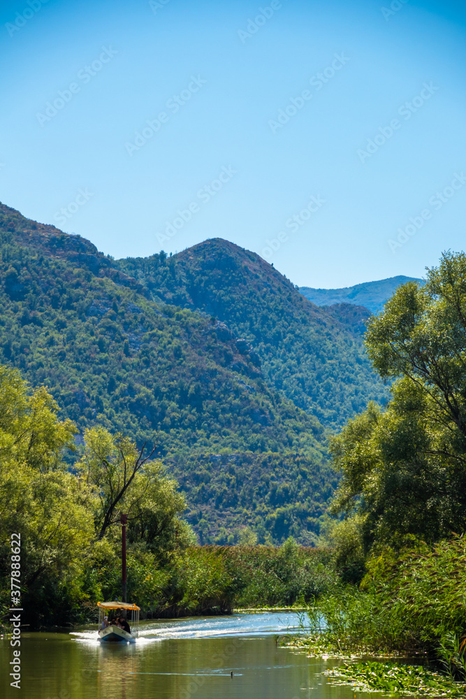 Vertical photo of the river between green tropical mountains and with a fishing boat Vertical photo of the river between green tropical mountains and with a fishing boat