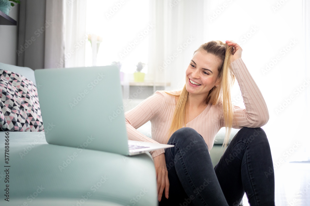 Relaxed woman enjoying time at home using laptop sitting near sofa Relaxed woman enjoying time at home using laptop sitting near sofa