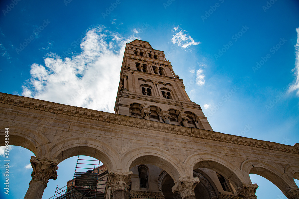 Torre de catedral de arcos detrás de muralla de arcos románicos