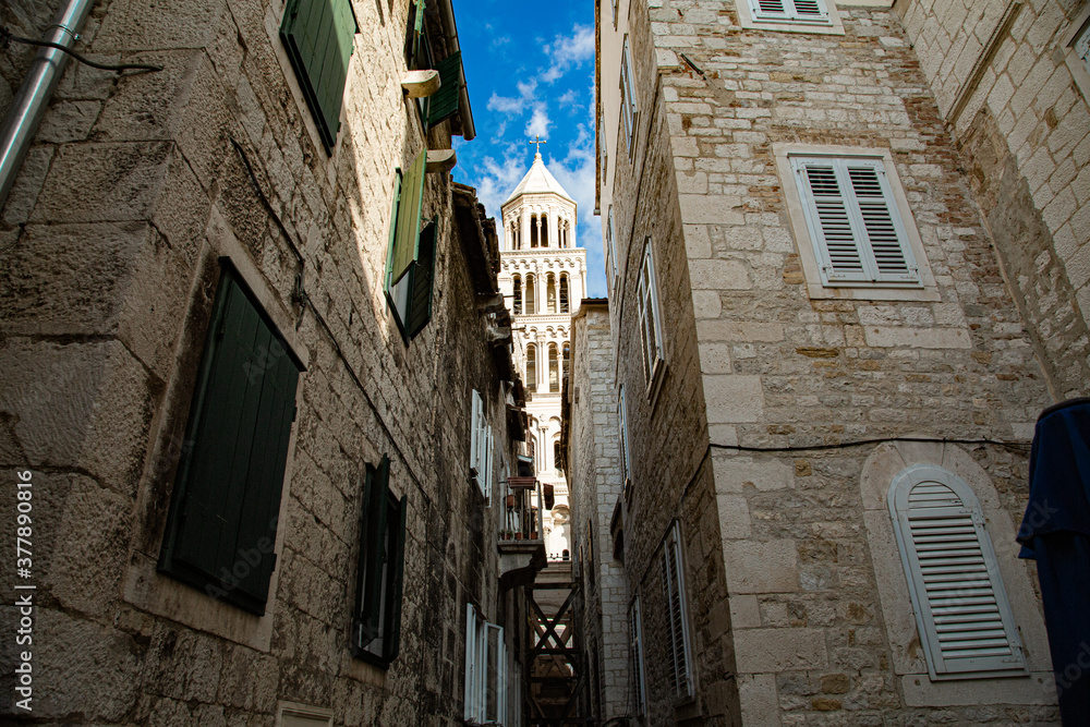 Torre de catedral desde pequeña calle con pilares de madera y ventanas
