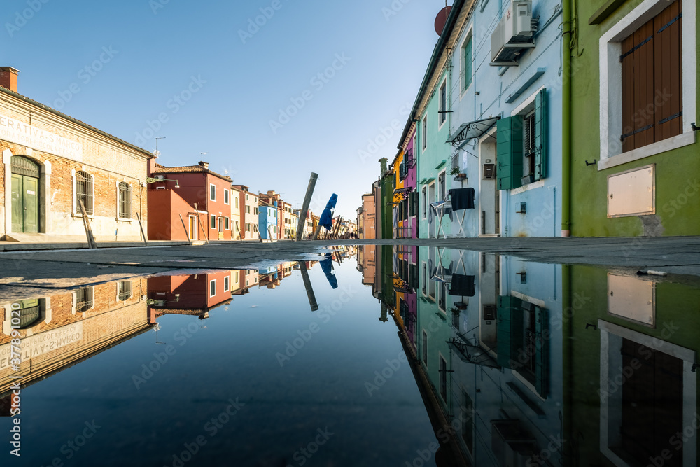 Reflection of the typical houses in a puddle on the Burano island, Veneto, Italy