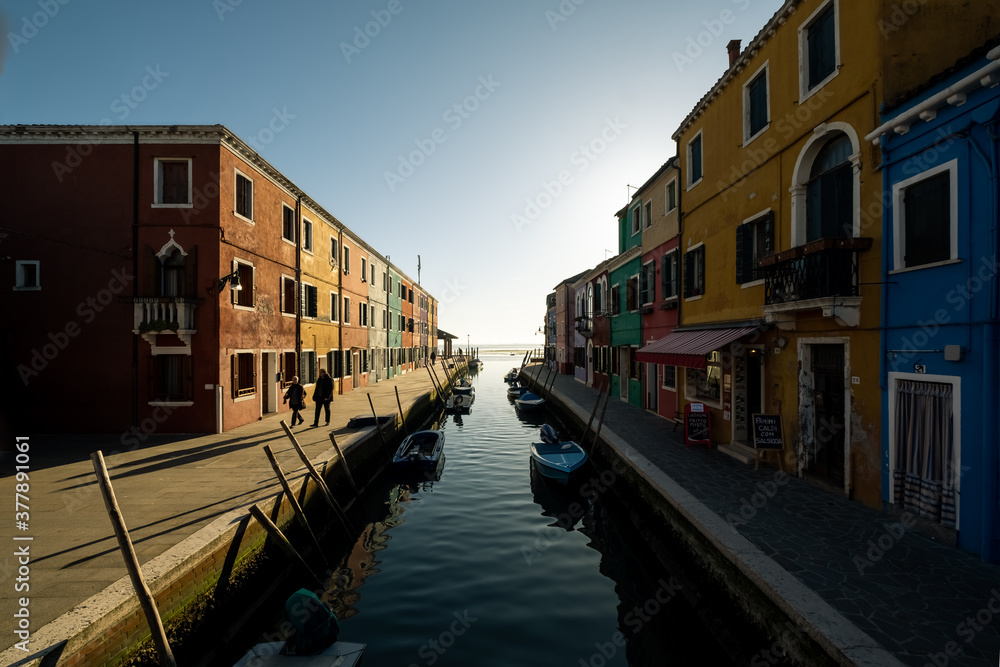 The view of colorful houses alongside the water canal on the Burano island during a sunset, Veneto, Italy