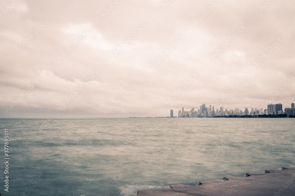 Part of Chicago skyline behind water of Lake Michigan on cloudy day