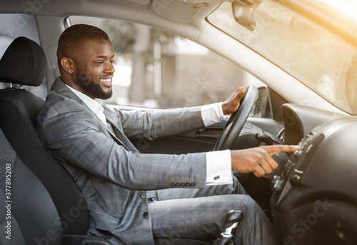 African man driver turning on music in car before moving