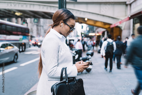 Black businesswoman standing on street with smartphone