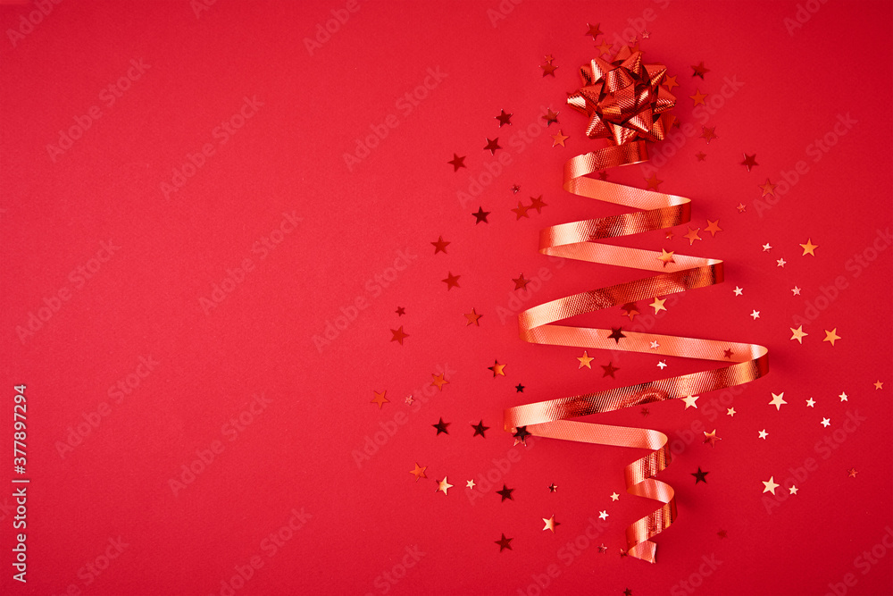 Christmas tree made from festive ribbon and confetti on a red background. Christmas decoration