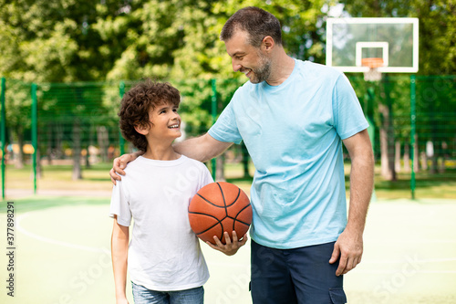 Man posing with son on basketball pitch front view