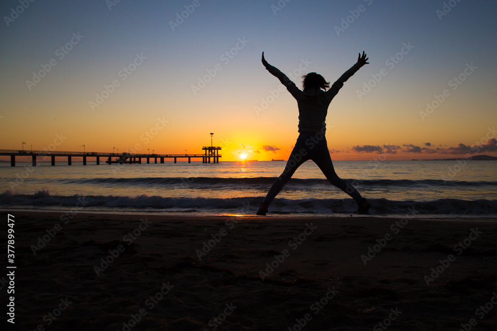 silhouette of a jumping person on the beach at sunset silhouette of a jumping person on the beach at sunset