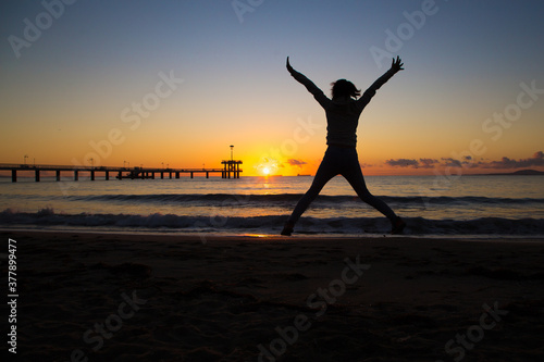 silhouette of a jumping person on the beach at sunset