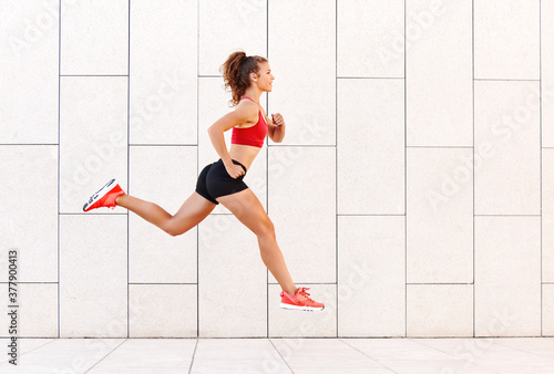 Concept of sporting success. strong girl runs and jumps high against the background of the city wall.