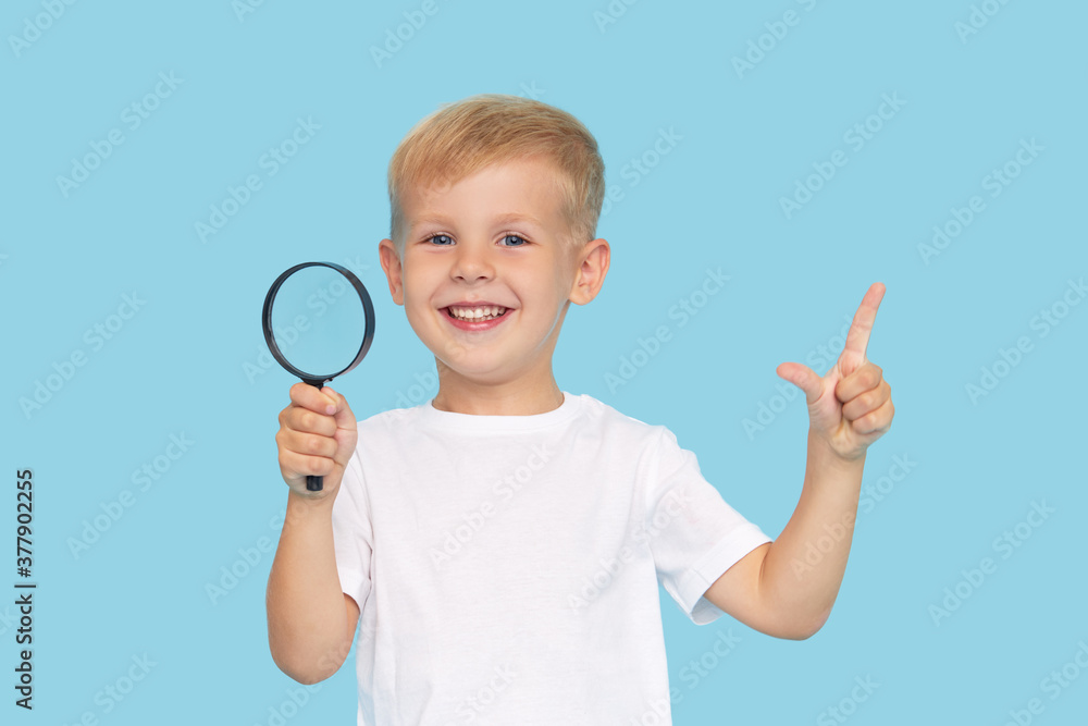 Cute child boy with magnifying glass on blue background. Investigation and discovery concept. Cute child boy with magnifying glass on blue background. Investigation and discovery concept.