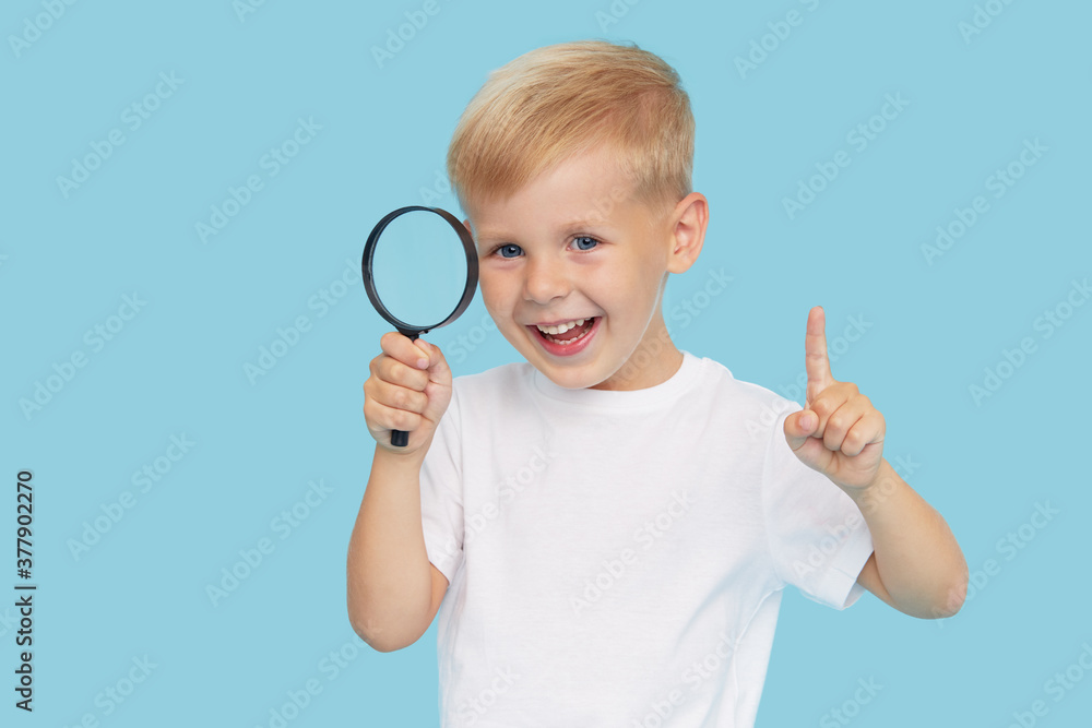 Cute child boy with magnifying glass on blue background. Investigation and discovery concept. Cute child boy with magnifying glass on blue background. Investigation and discovery concept.