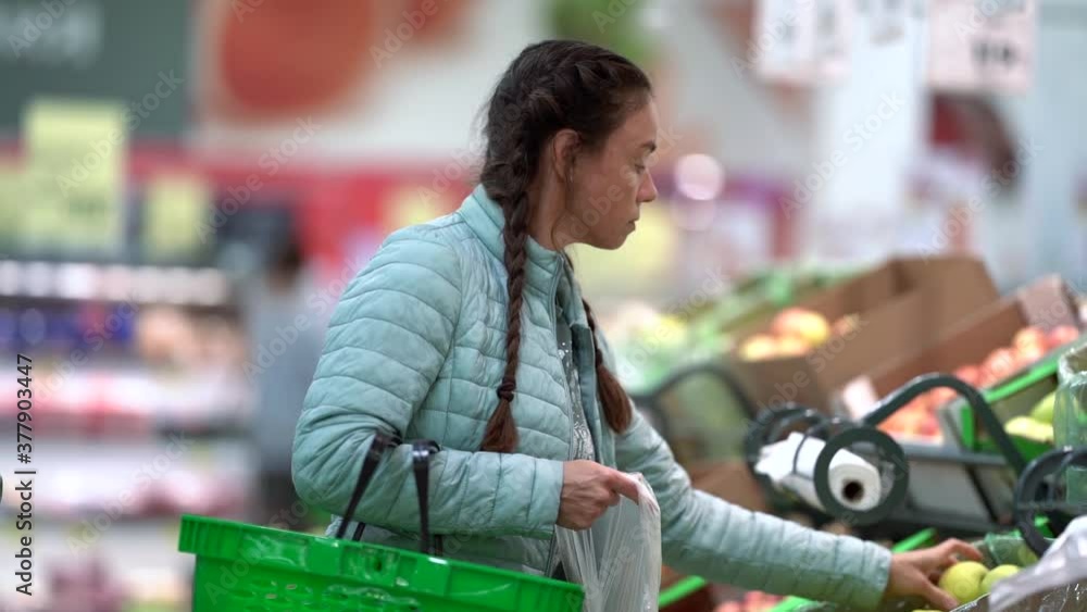 A woman chooses fresh apples in a grocery store supermarket sale shopping market food A woman chooses fresh apples in a grocery store supermarket sale shopping market food