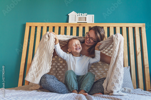 mom and child have fun in the bedroom on the bed under the blank photo