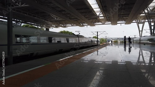 Static footage of Shanghai railway station high speed train leaving on the left and man carrying briefcase walking towards the camera very shiney and polished floor 4k high resolution quality photo